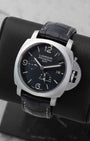 Angled front view of a preowned 2011 Panerai Luminor 1950 GMT PAM00321 featuring a black sandwich dial, date display, GMT hand, and power reserve indicator