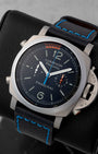 Angled view of Panerai PAM00526 displaying black dial, regatta countdown scale, orange and blue hands, and titanium case