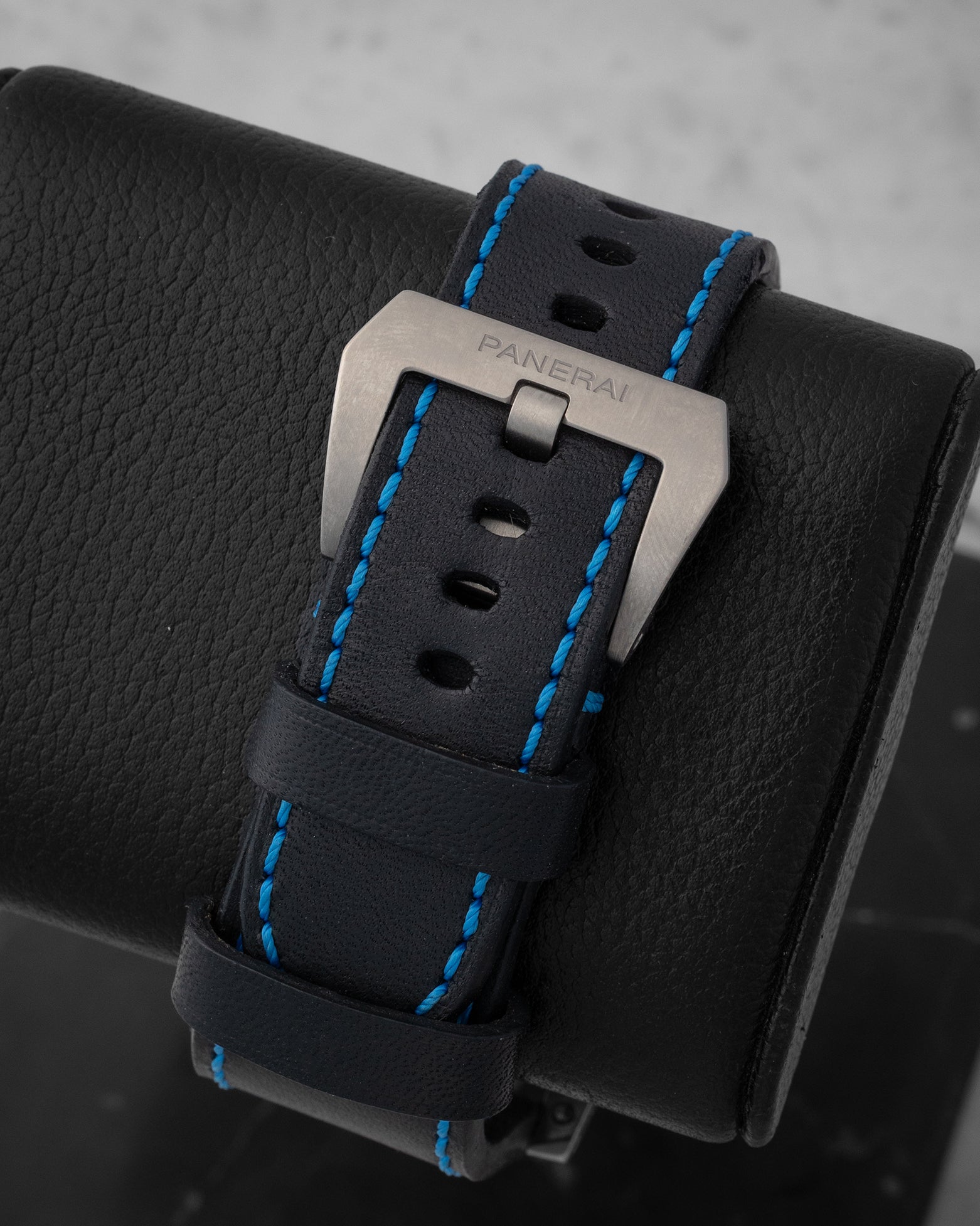 Black leather watch strap with blue contrast stitching and brushed titanium pin buckle on Panerai PAM00526
