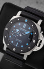 Angled view of Panerai Submersible PAM00799 showing black dial, cyan blue luminous markers, and Carbotech bezel