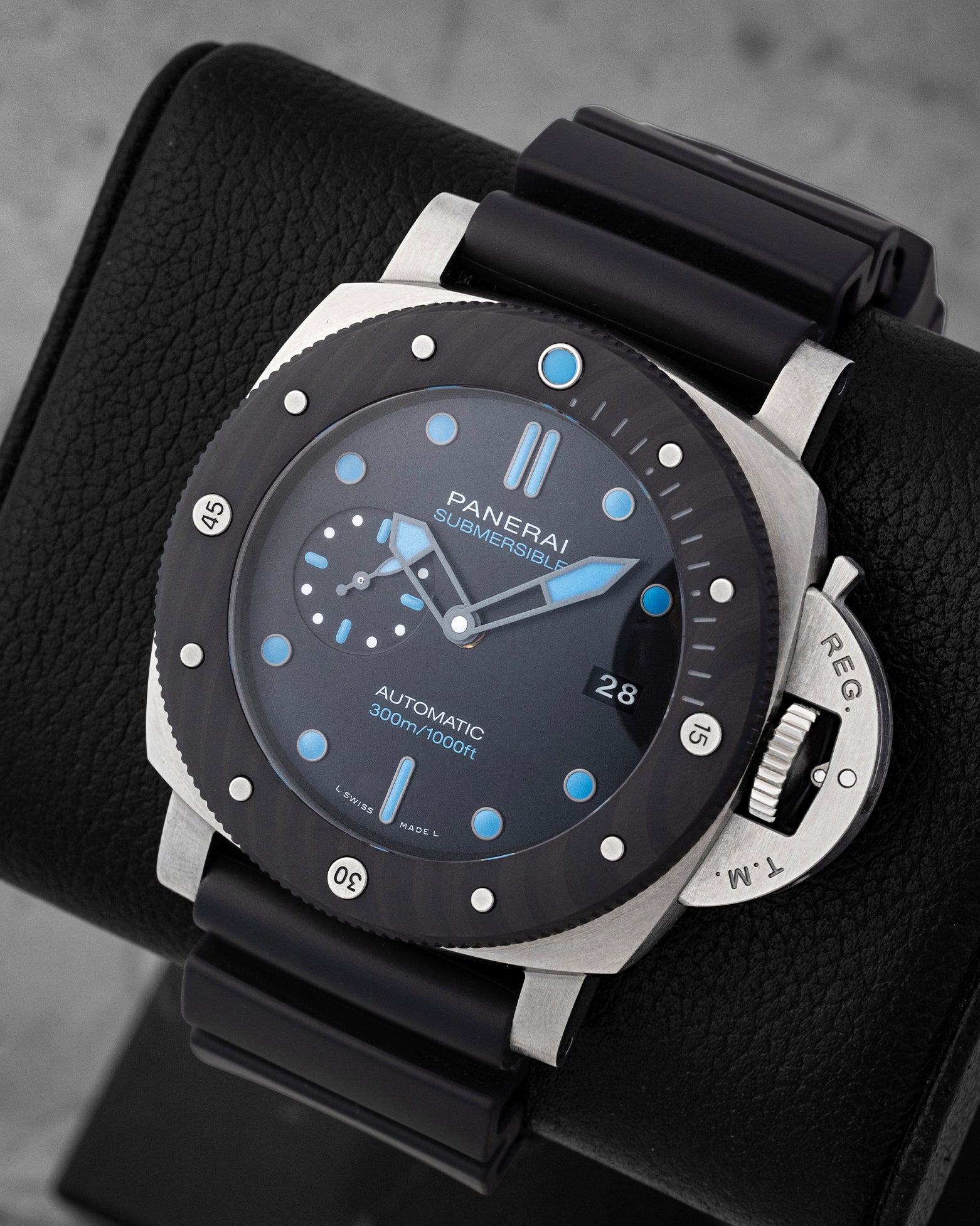 Angled view of Panerai Submersible PAM00799 showing black dial, cyan blue luminous markers, and Carbotech bezel