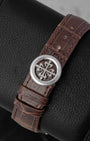 Close-up shot of the solid platinum foldover deployment clasp engraved with the iconic Patek Philippe Cross on a matte brown alligator strap