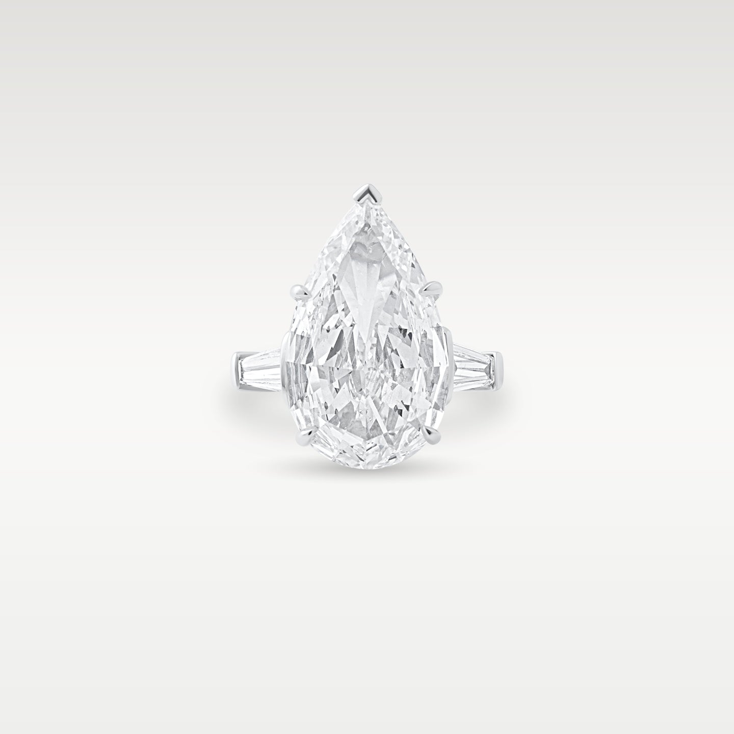 Front view of a platinum engagement ring featuring a large pear-cut diamond flanked by tapered baguette side stones from Noah's Fine Watches & Jewelry in Dallas, TX