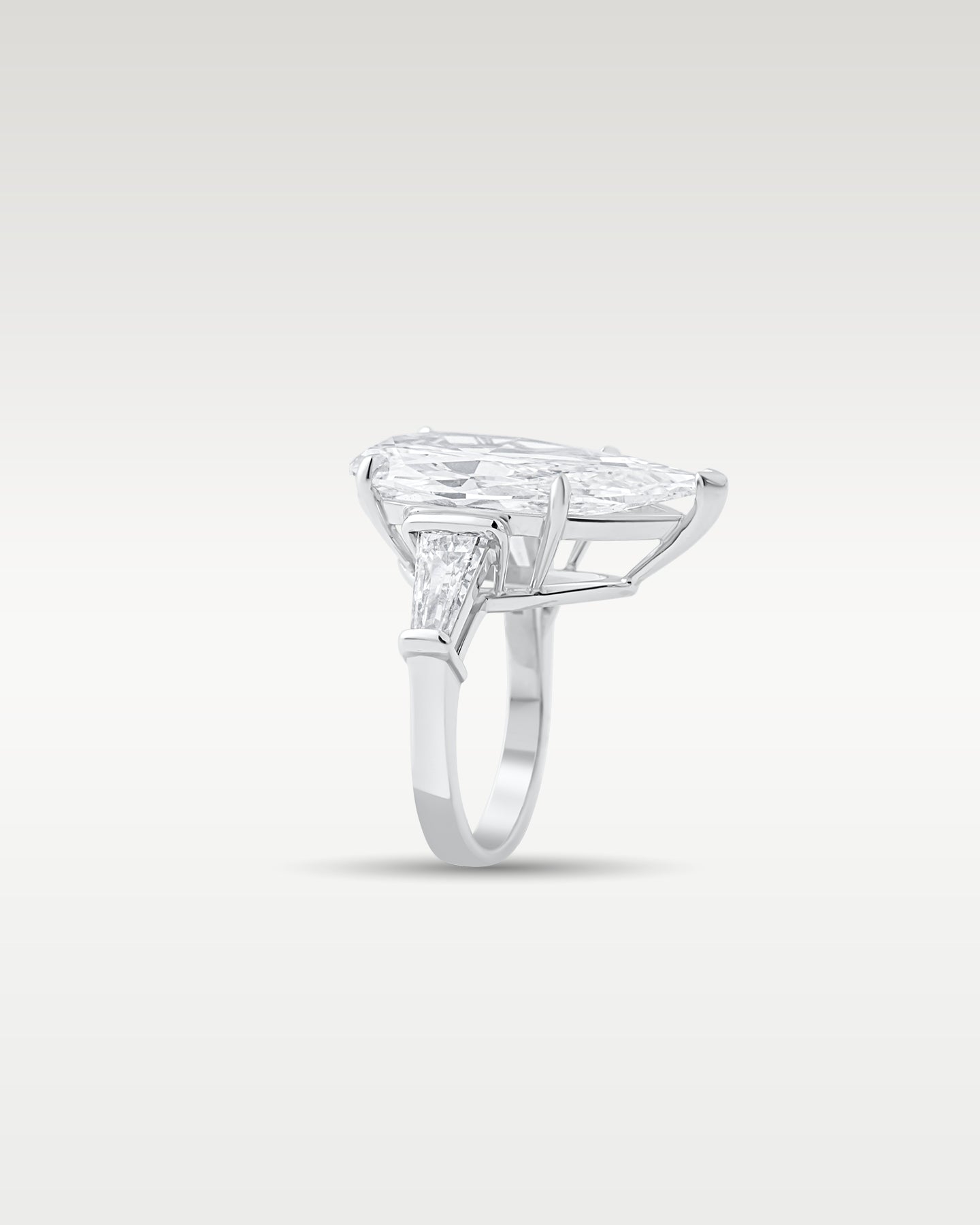 Side profile showing the low basket setting and platinum band structure of a pear-cut diamond ring with tapered baguettes