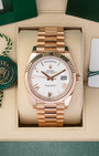 A preowned 2023 Rolex Day-Date 40 reference 228235 in 18k Everose gold featuring a crisp white dial with faceted rose gold Roman numeral hour markers inside its presentation box at Noah's Fine Watches & Jewelry in Dallas