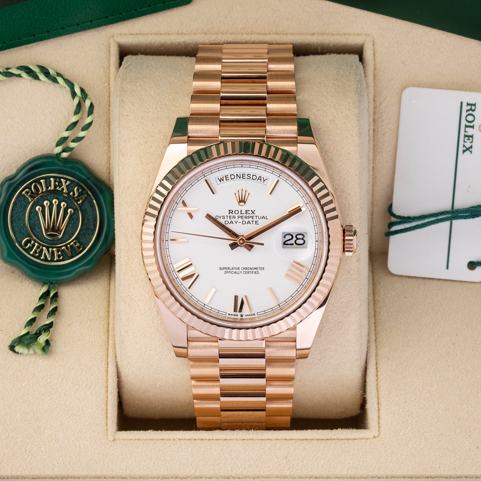 A preowned 2023 Rolex Day-Date 40 reference 228235 in 18k Everose gold featuring a crisp white dial with faceted rose gold Roman numeral hour markers inside its presentation box at Noah's Fine Watches & Jewelry in Dallas