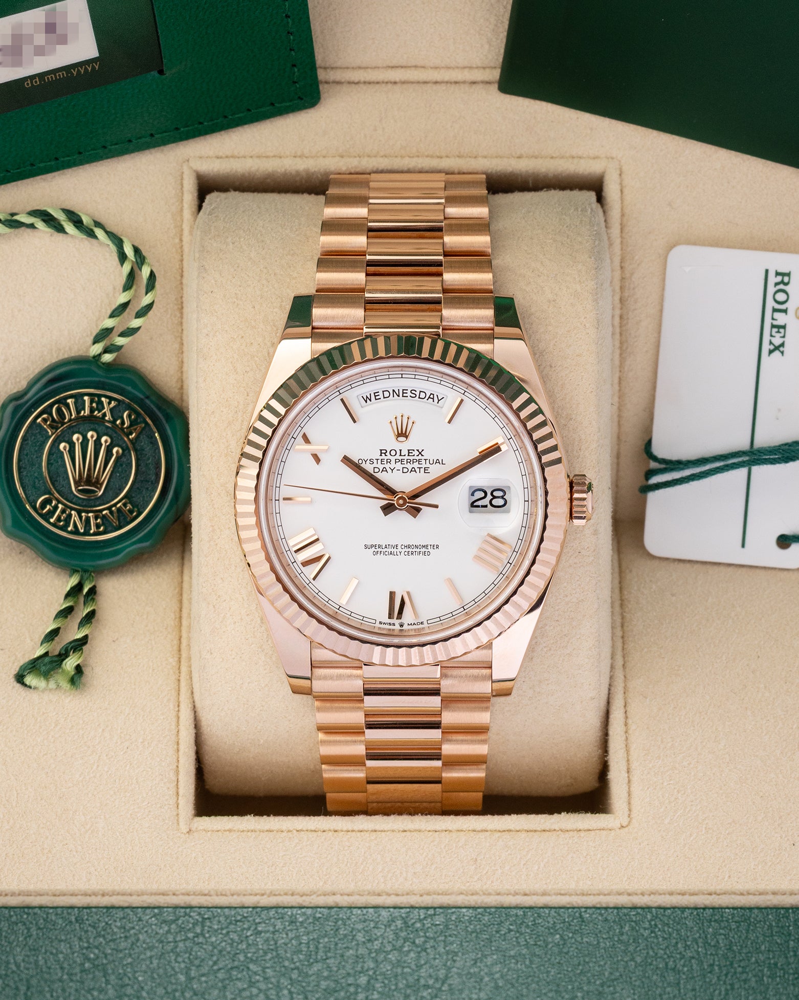 A preowned 2023 Rolex Day-Date 40 reference 228235 in 18k Everose gold featuring a crisp white dial with faceted rose gold Roman numeral hour markers inside its presentation box at Noah's Fine Watches & Jewelry in Dallas