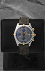 A preowned Breitling Chronomat reference B13050 in stainless steel and 18k yellow gold featuring a slate grey dial on a premium dark leather strap at Noah's Fine Watches & Jewelry in Dallas