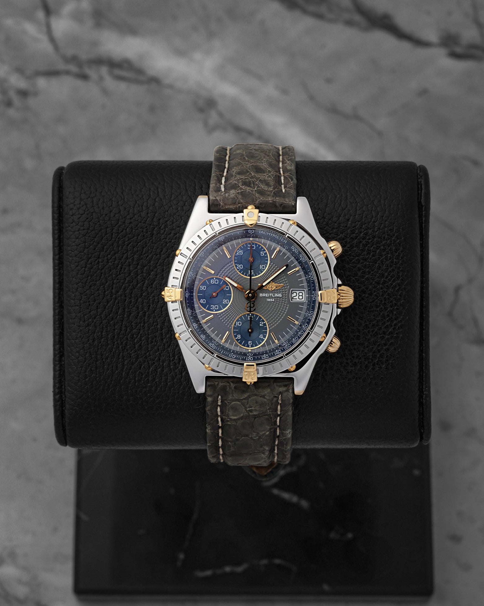 A preowned Breitling Chronomat reference B13050 in stainless steel and 18k yellow gold featuring a slate grey dial on a premium dark leather strap at Noah's Fine Watches & Jewelry in Dallas