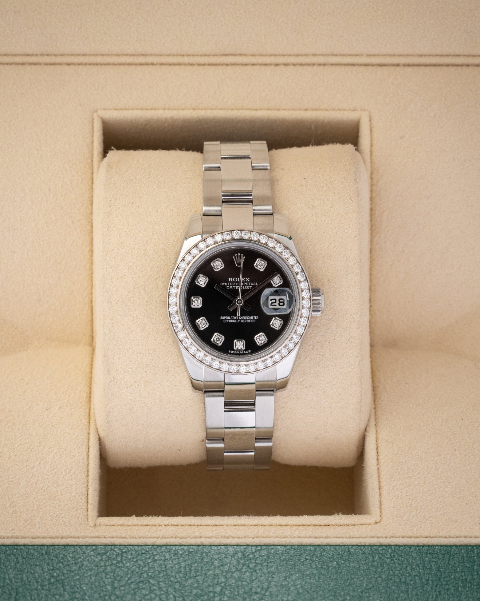 A ladies' pre-owned Rolex Lady-Datejust 26 reference 179384 featuring a black sunburst dial, factory diamond hour markers, and a diamond-set bezel inside its box at Noah's Fine Watches & Jewelry in Dallas