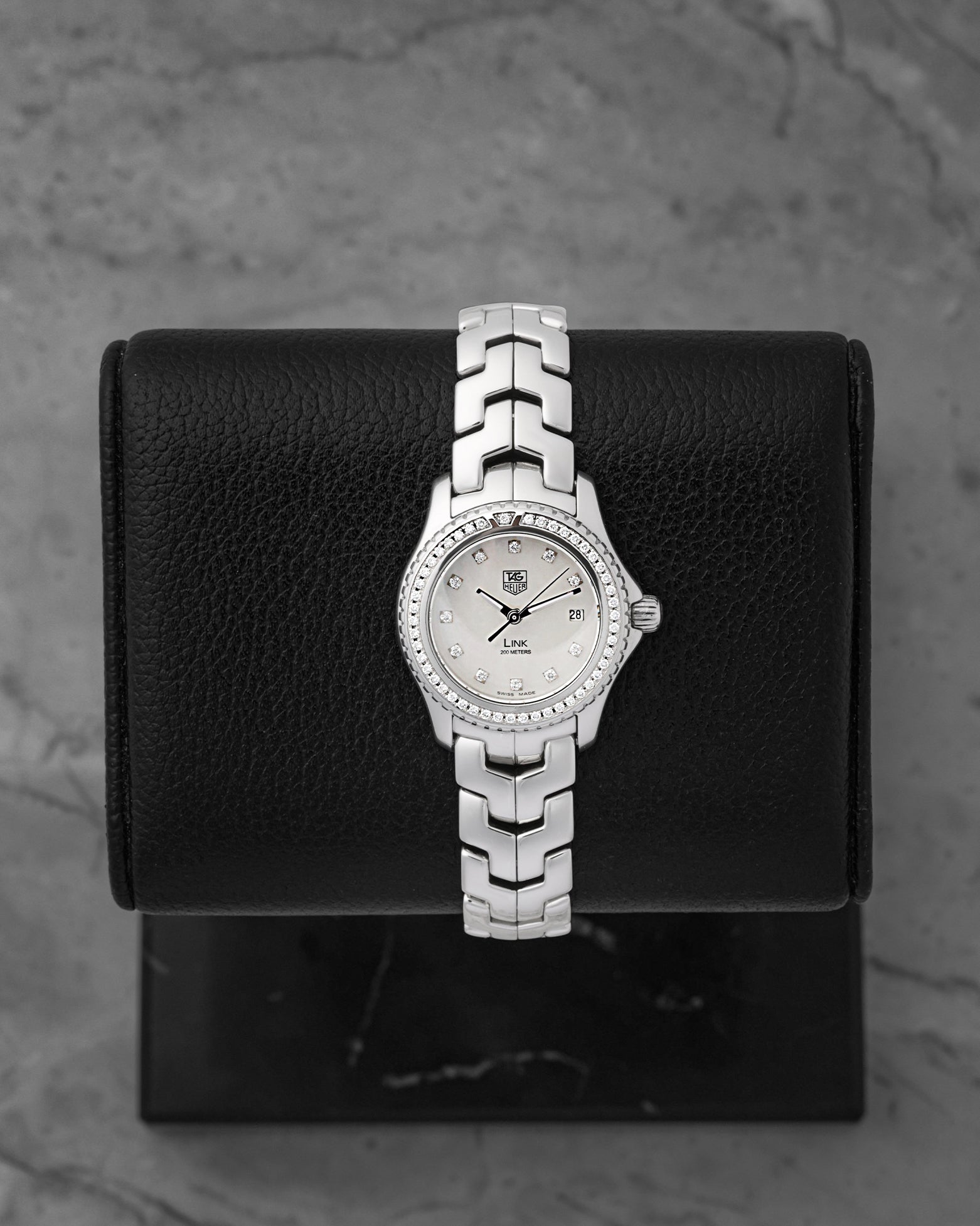 A ladies' pre-owned TAG Heuer Link reference WJF131A featuring an iridescent white mother-of-pearl dial with diamond hour markers and a diamond-set bezel at Noah's Fine Watches & Jewelry in Dallas