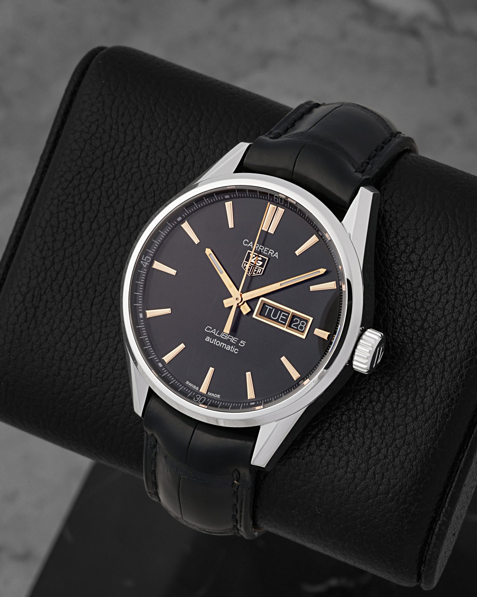 A high-angle three-quarter view of the 41mm stainless steel Carrera case highlighting its polished fixed bezel and faceted rose gold indices on a black leather cushion