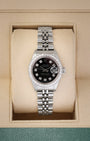 A ladies' pre owned 2000 Rolex Lady-Datejust reference 79174 featuring a custom black dial, diamond hour markers, and a custom diamond-set bezel inside its box at Noah's Fine Watches & Jewelry in Dallas