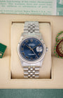 A pre owned 2002 Rolex Datejust 36 reference 16234 in stainless steel featuring a blue sunburst dial with applied white gold Roman numerals and a fluted bezel inside its presentation box at Noah's Fine Watches & Jewelry in Dallas