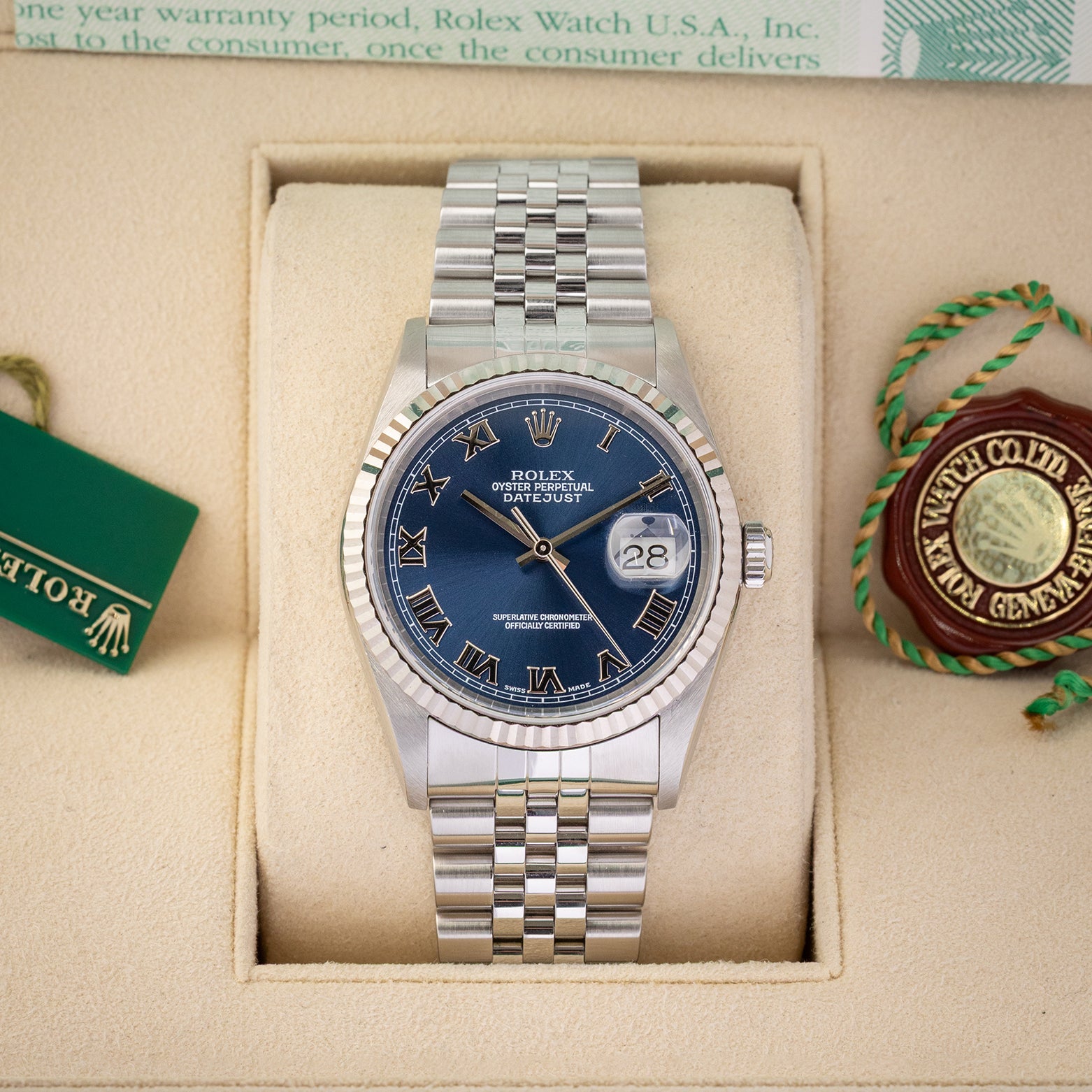 A pre owned 2002 Rolex Datejust 36 reference 16234 in stainless steel featuring a blue sunburst dial with applied white gold Roman numerals and a fluted bezel inside its presentation box at Noah's Fine Watches & Jewelry in Dallas