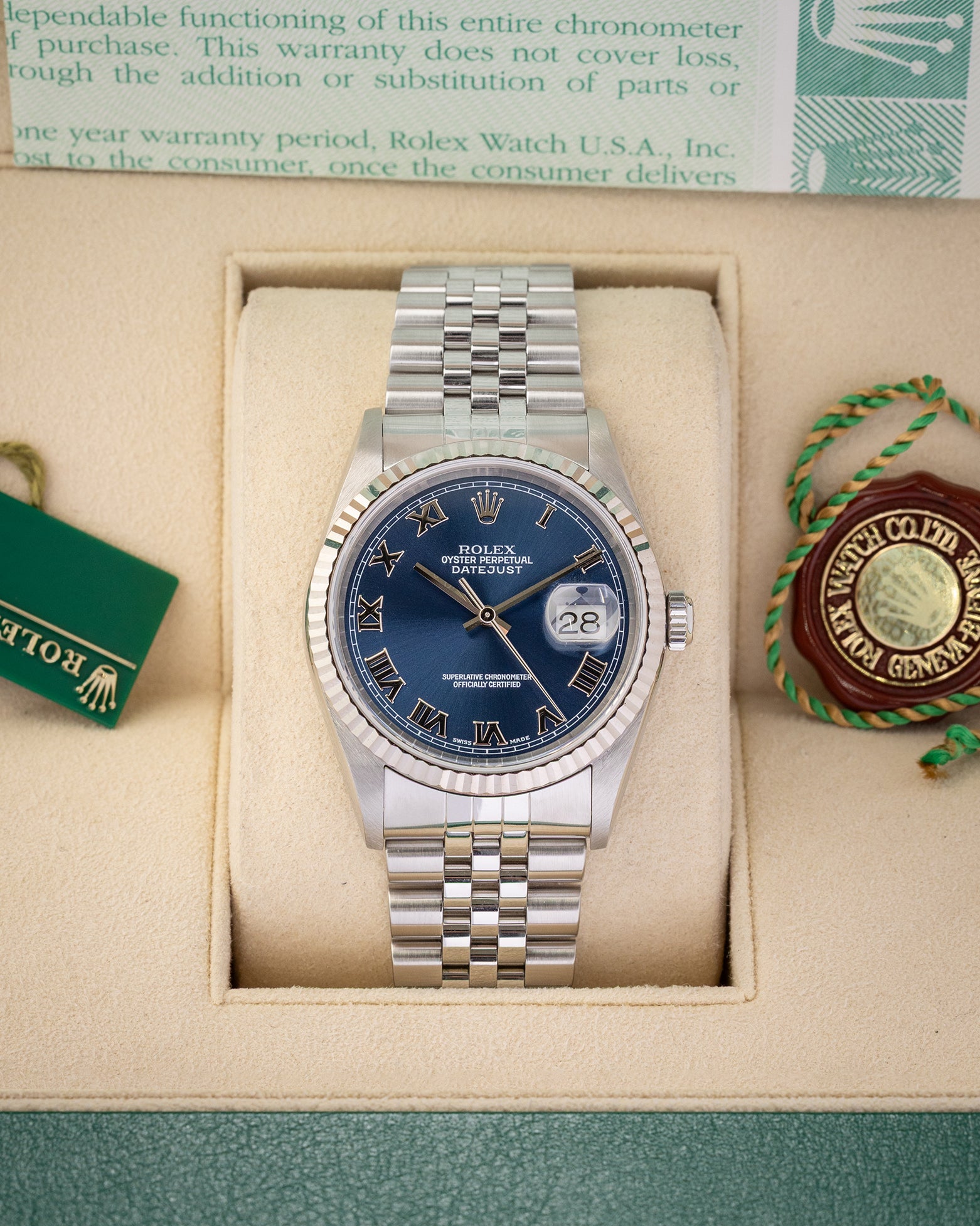 A pre owned 2002 Rolex Datejust 36 reference 16234 in stainless steel featuring a blue sunburst dial with applied white gold Roman numerals and a fluted bezel inside its presentation box at Noah's Fine Watches & Jewelry in Dallas