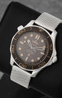 angled perspective of the 42mm Grade 2 Titanium Omega Seamaster NTTD highlighting the matte tropical brown aluminum dial and vintage-style broad arrow marking