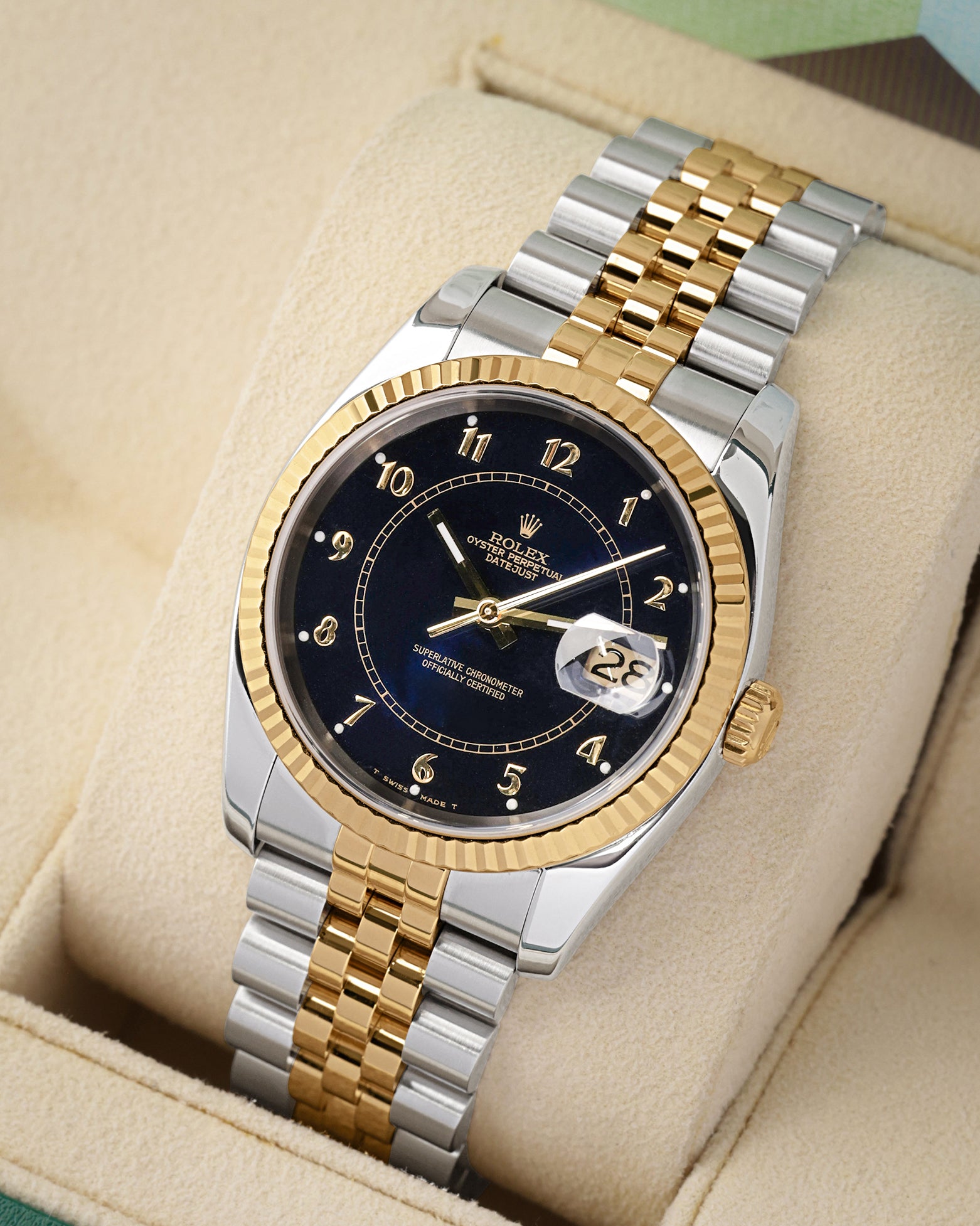 angled perspective of a two-tone Rolex Datejust 36 highlighting the custom blue boiler gauge dial, 18k yellow gold fluted bezel, and steel links