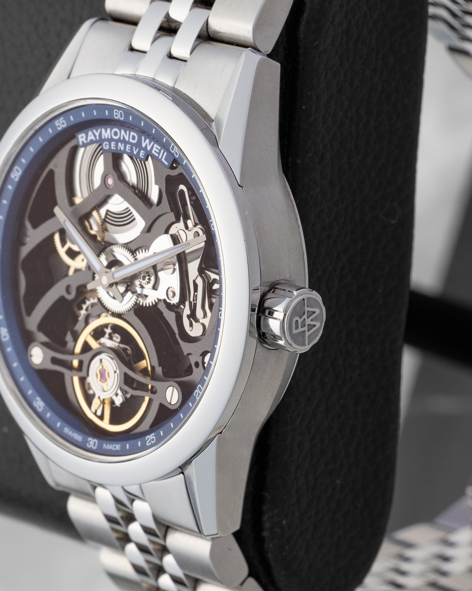 Close-up side profile of a brushed steel watch case showing the fluted crown embossed with the RW brand monogram
