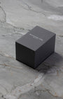 Original dark grey rectangular Raymond Weil luxury watch presentation storage box resting on a grey marble table