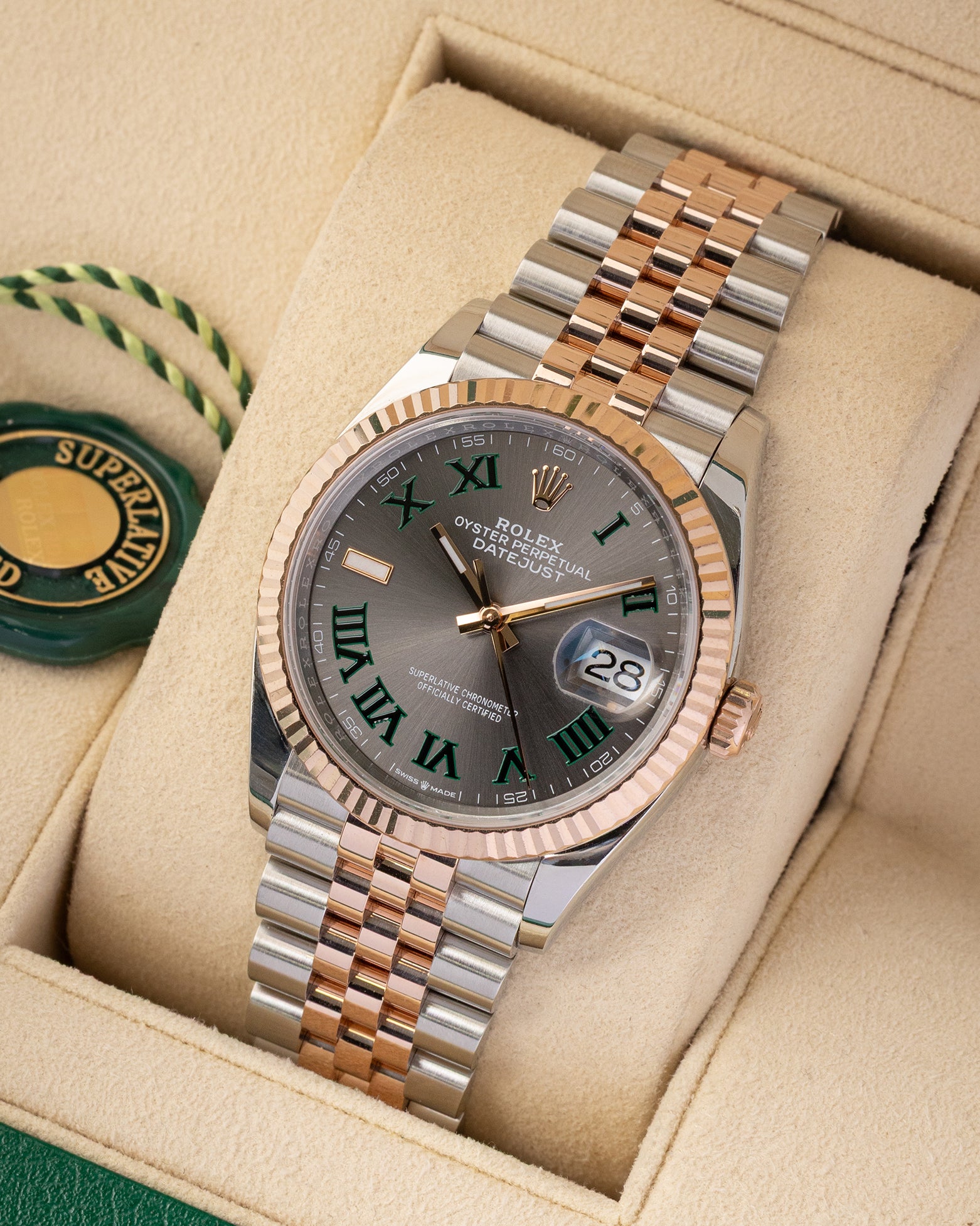studio portrait of the 36mm luxury watch case showcasing its 18k Everose gold fluted bezel and polished rose gold center Jubilee links on a beige cushion