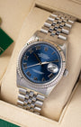 portrait of the 36mm luxury watch case showcasing its 18k white gold fluted bezel and classic five-piece link steel Jubilee bracelet on a beige cushion