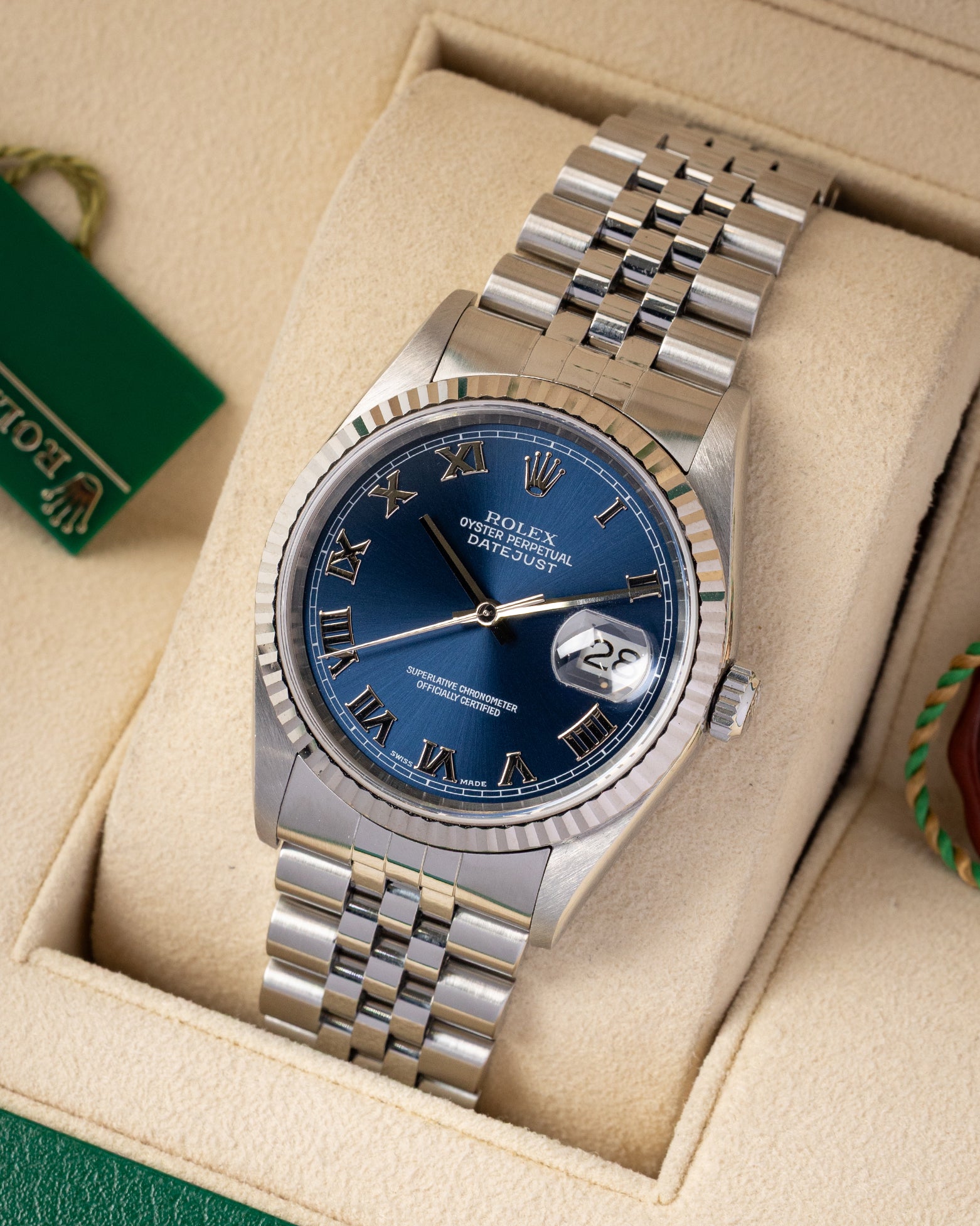 portrait of the 36mm luxury watch case showcasing its 18k white gold fluted bezel and classic five-piece link steel Jubilee bracelet on a beige cushion