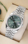 An angled studio profile view of the stainless steel Rolex Datejust 36 mint green dial watch resting on a cream display cushion
