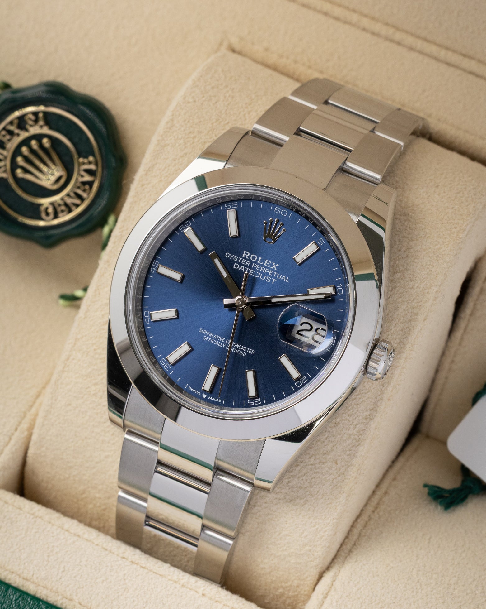 angled top-down studio view of the stainless steel Rolex Datejust 41 blue dial watch resting on a cream leather watch pillow