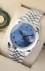 An angled studio profile view of a stainless steel Rolex Datejust 41 watch resting on a cream display cushion