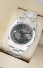 An angled studio profile view of a stainless steel 41mm Rolex Datejust Wimbledon watch resting on a cream display cushion