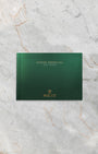 The clean front profile view of the dark green official Rolex Day-Date user instruction manual booklet detailed with a gold embossed crown insignia logo