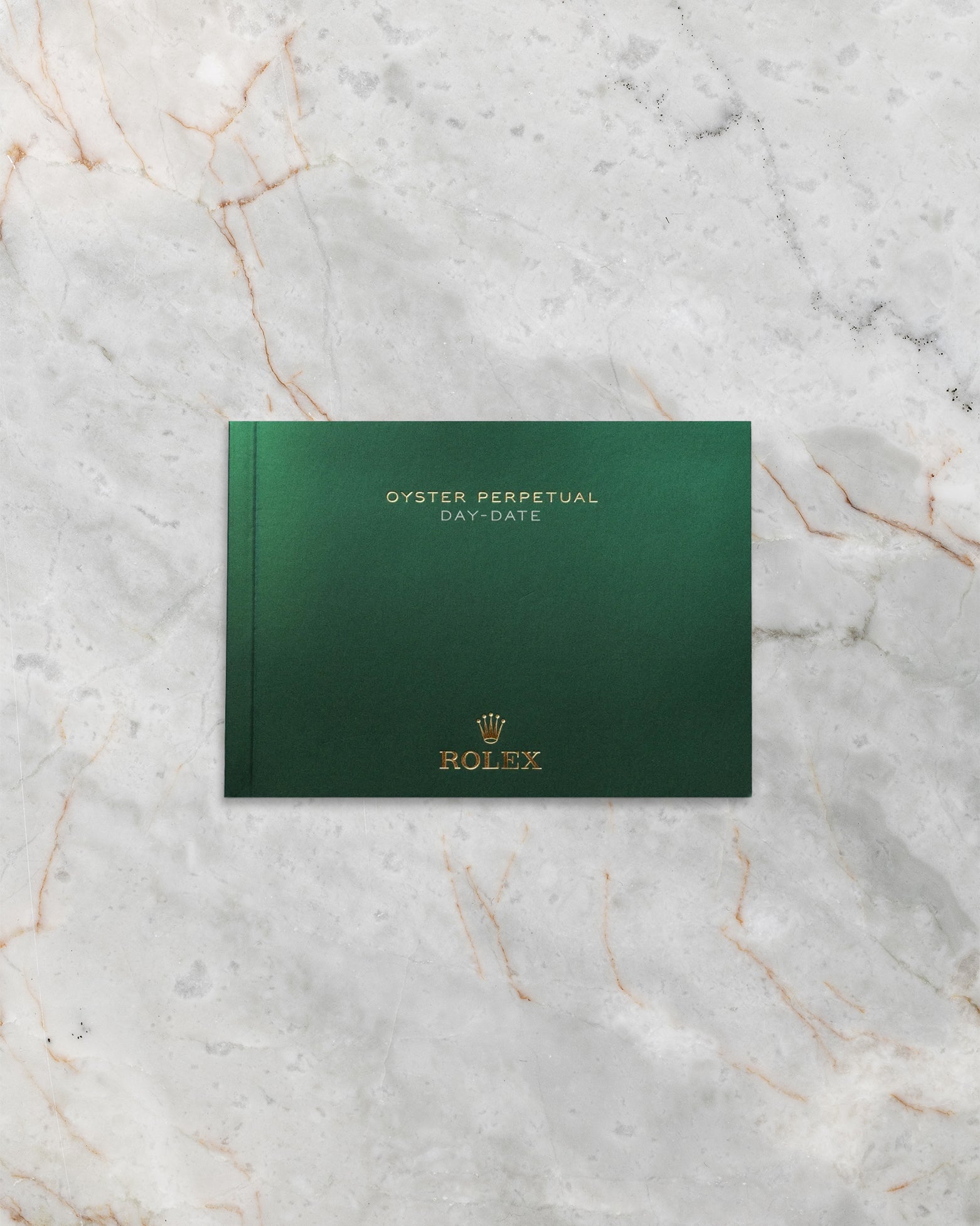 The clean front profile view of the dark green official Rolex Day-Date user instruction manual booklet detailed with a gold embossed crown insignia logo