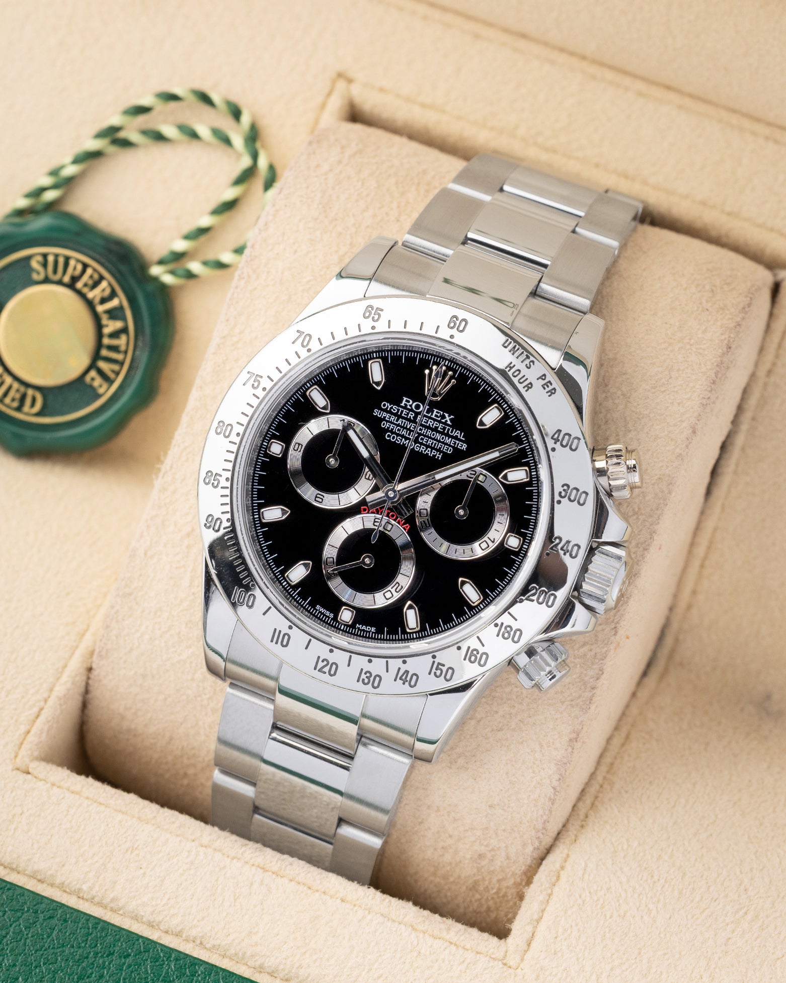 angled profile view of a pre-owned steel Rolex Daytona reference 116520 showcasing the black racing dial on its presentation cushion