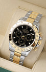 angled profile view of a pre-owned two-tone Rolex Daytona reference 116523 showcasing the black dial and steel and 18k yellow gold Oyster bracelet
