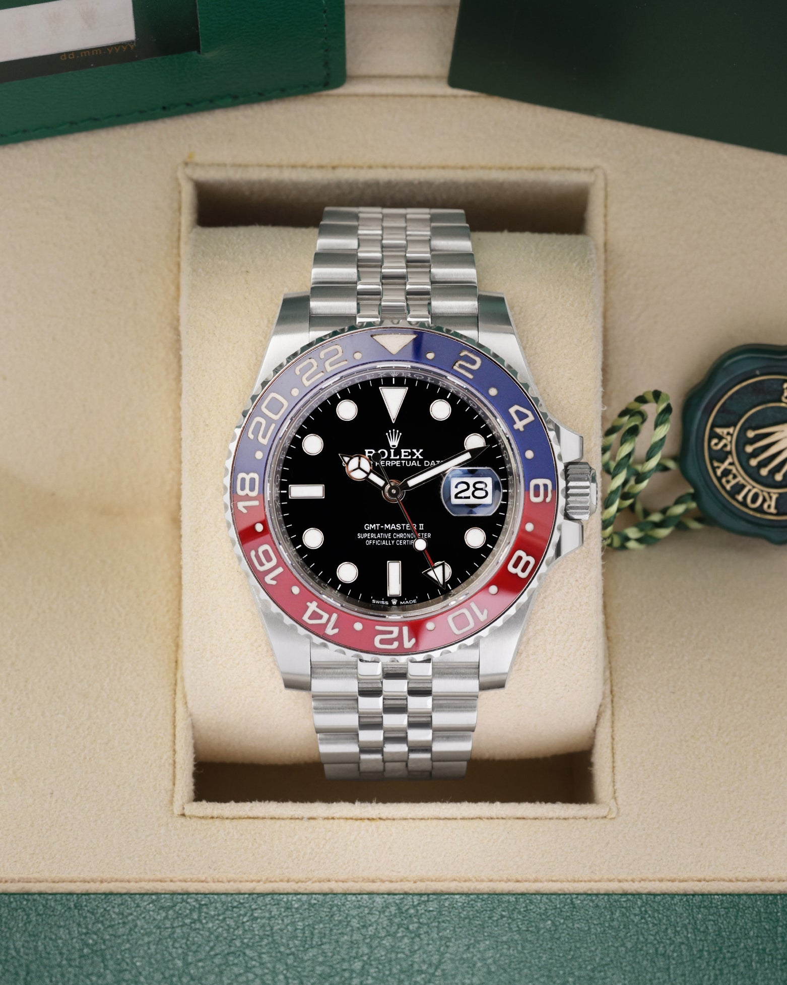 Front portrait view of a pre-owned 2022 Rolex GMT-Master II Ref 126710BLRO Pepsi watch resting in its original green presentation box, available at Noahs Fine Watches and Jewelry Dallas