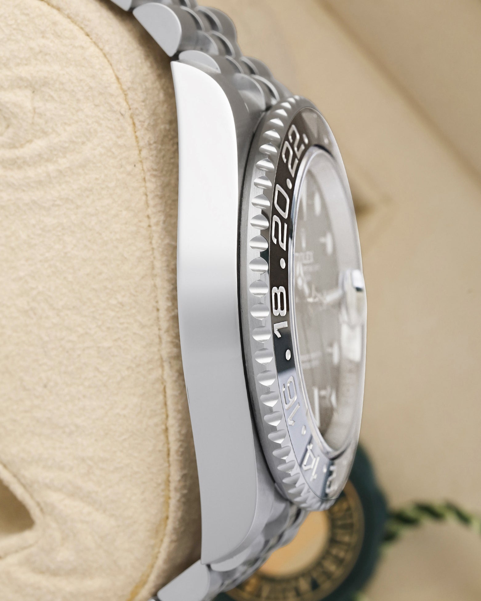 left-side case profile view of a pre-owned 40mm stainless steel Rolex GMT-Master II watch case resting on a presentation cushion