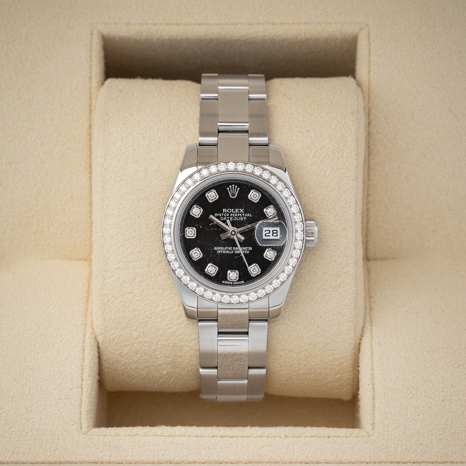 balanced front studio portrait of a 26mm Rolex Lady-Datejust 179384 watch with a black diamond dial and factory diamond bezel inside its presentation box