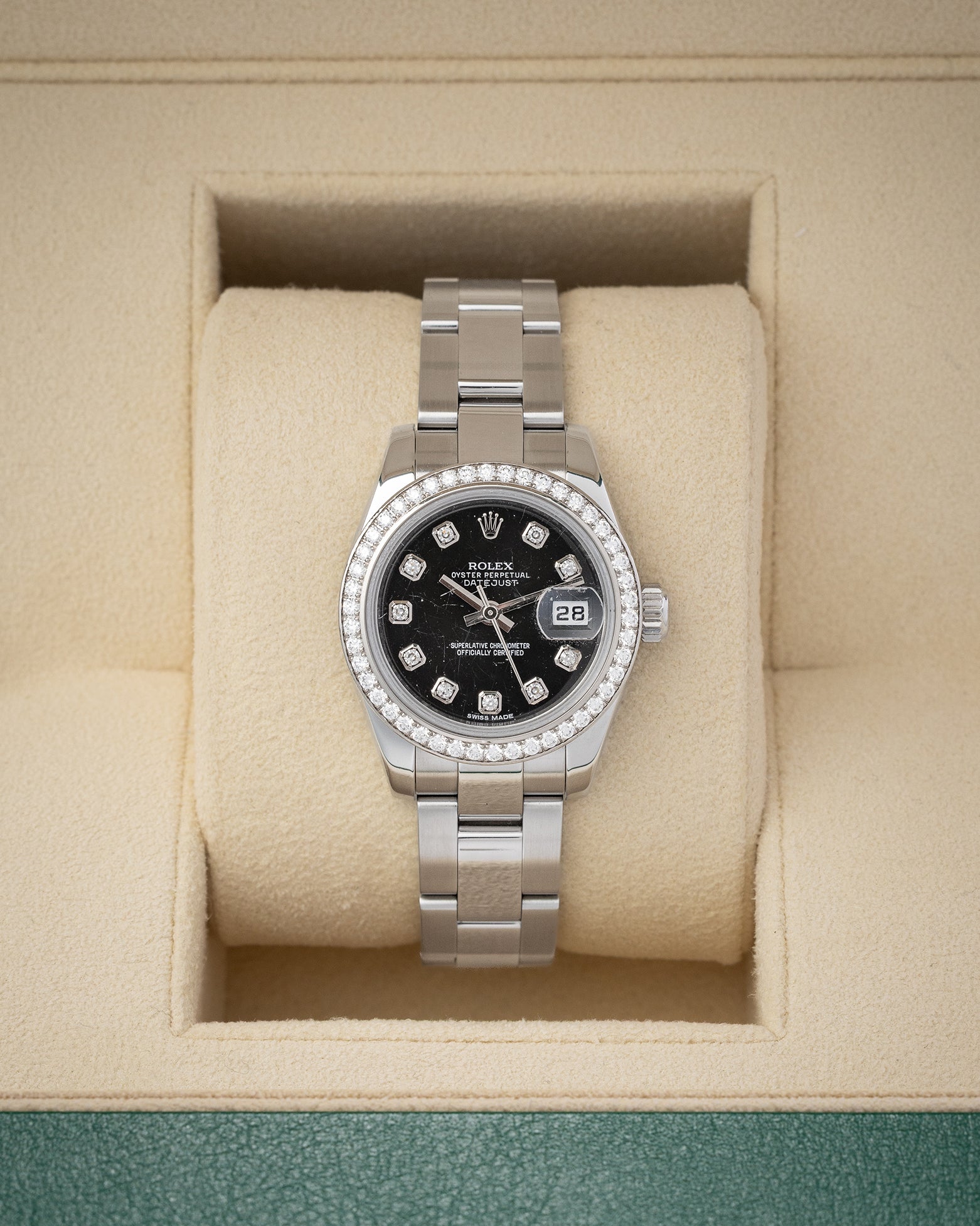 balanced front studio portrait of a 26mm Rolex Lady-Datejust 179384 watch with a black diamond dial and factory diamond bezel inside its presentation box