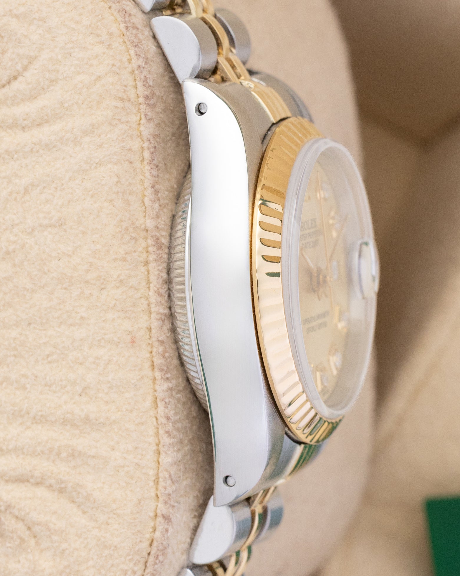 left-side case profile view of a vintage steel and 18k yellow gold 26mm Rolex Oyster case resting on a presentation cushion