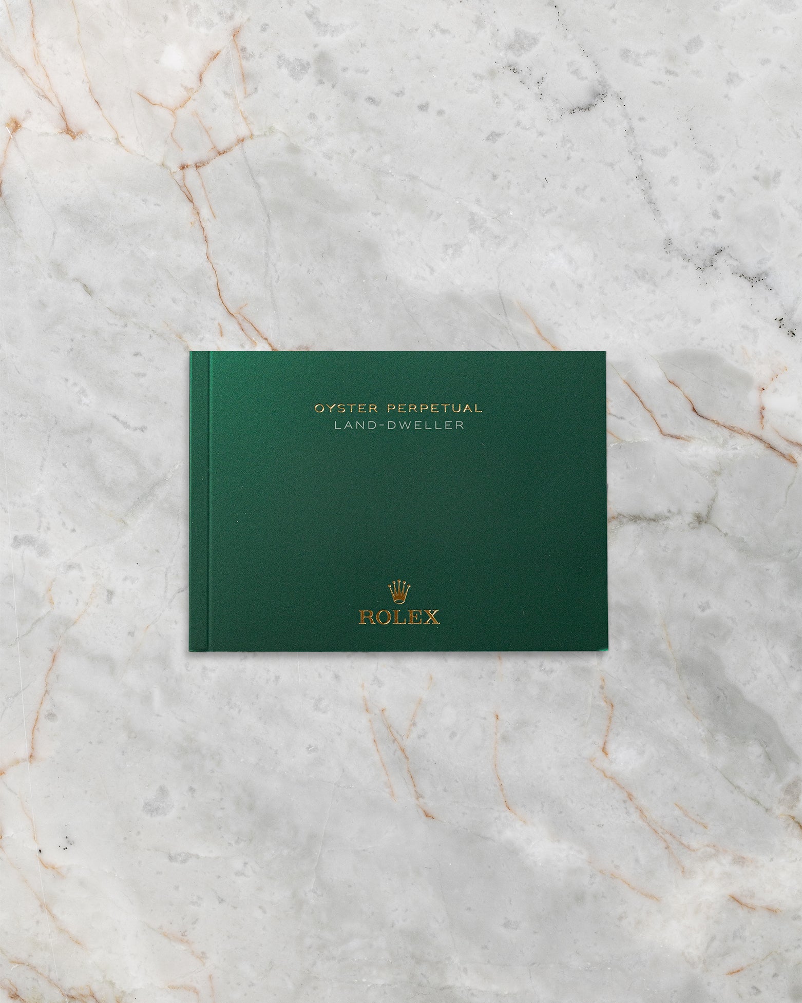The clean front profile view of the dark green official Rolex Land-Dweller user manual booklet detailing the mechanical operation of the sequential distribution Dynapulse escapement
