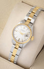 An angled studio profile shot of a 1969 two-tone Rolex Oyster Perpetual Date watch on a cream velvet cushion