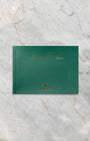The official green Rolex Oyster Perpetual user guide booklet and instruction documentation laid flat on a gray marble background