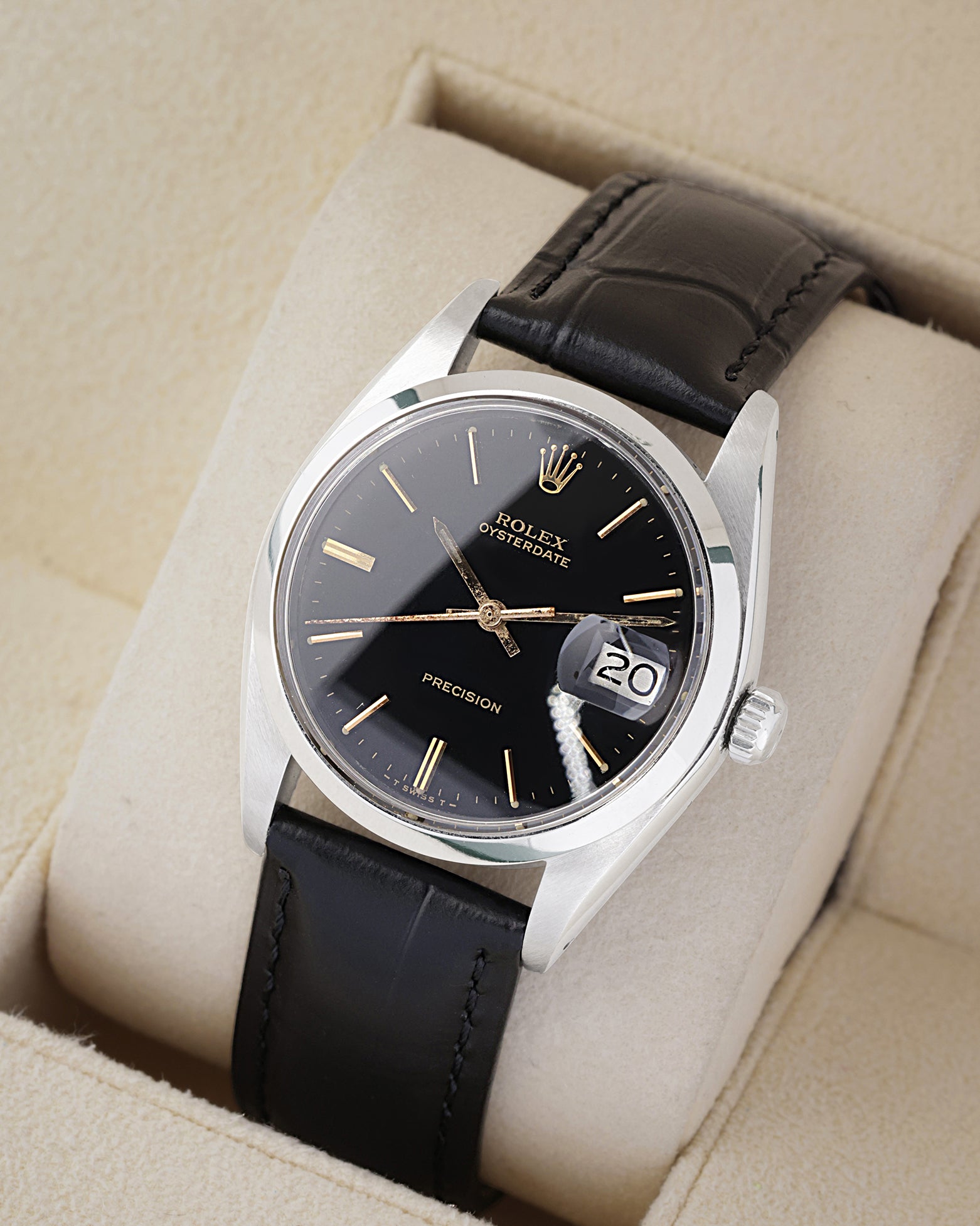 An angled studio profile shot of the stainless steel case and black leather strap of a vintage Rolex Oysterdate 6694 watch