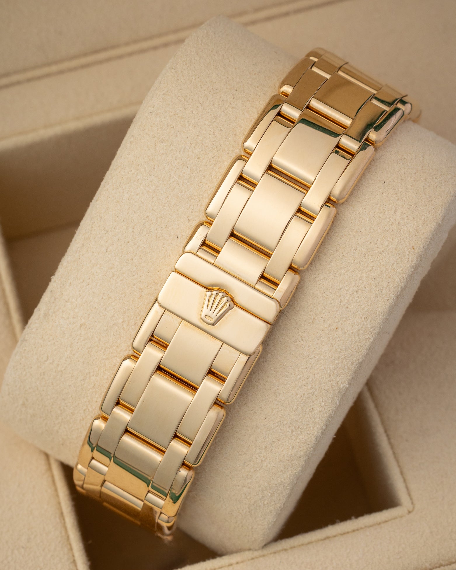 A rear view of the rounded five-piece yellow gold link watch band focusing on the completely flush closure of the seamless hidden folding Crownclasp detailed with a miniature raised Rolex crest logo