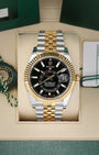 Front view of a pre-owned 2021 Rolex Sky-Dweller Ref 326933 yellow Rolesor two-tone watch with a bright black index dial and Jubilee bracelet, on display at Noahs Fine Watches and Jewelry Dallas