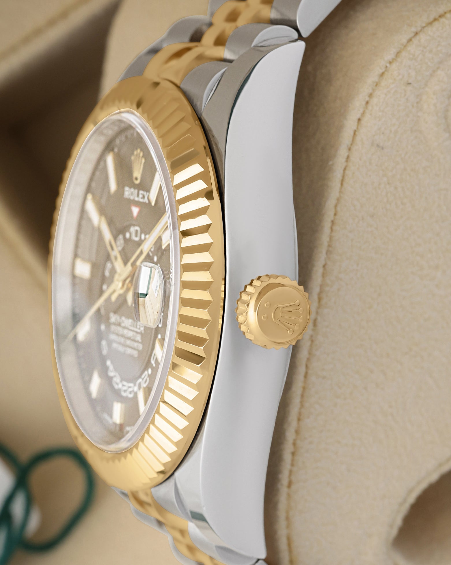 Side profile focusing on the polished Oystersteel case tier and the 18k yellow gold screw-down winding crown of the Rolex Sky-Dweller