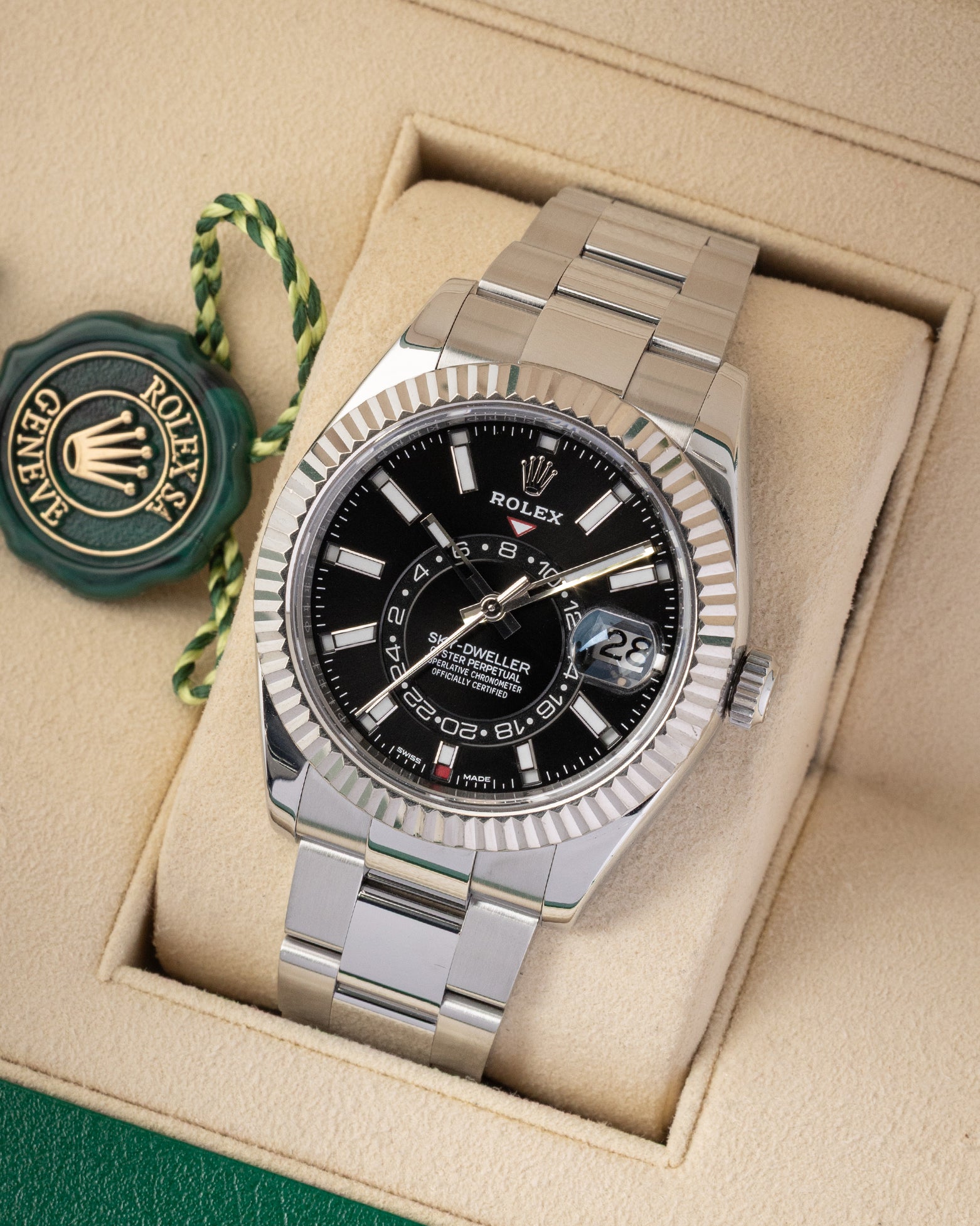 e-commerce portrait of the 42mm Sky-Dweller showcasing the Saros annual calendar red month indicator windows and solid Oyster bracelet on a beige display cushion