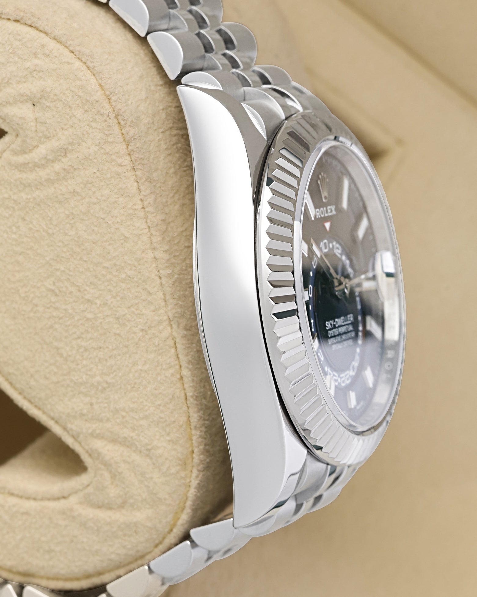Polished left-side case profile view of a pre-owned 42mm Oystersteel Rolex Sky-Dweller watch case resting on a presentation cushion