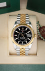 Front view of a pre-owned 2023 Rolex Sky-Dweller Ref 336933 yellow Rolesor two-tone watch with a bright black index dial and Jubilee bracelet, on display at Noahs Fine Watches and Jewelry Dallas